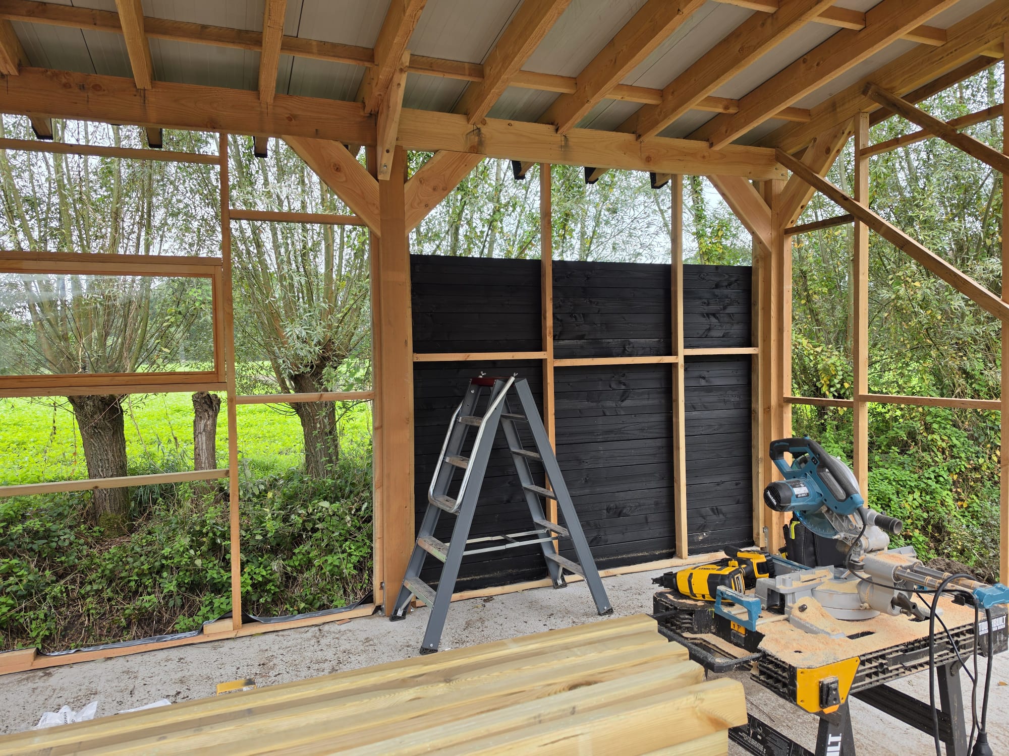 Interieur van de schuur met zwart gelamineerd wanddeel en gereedschap