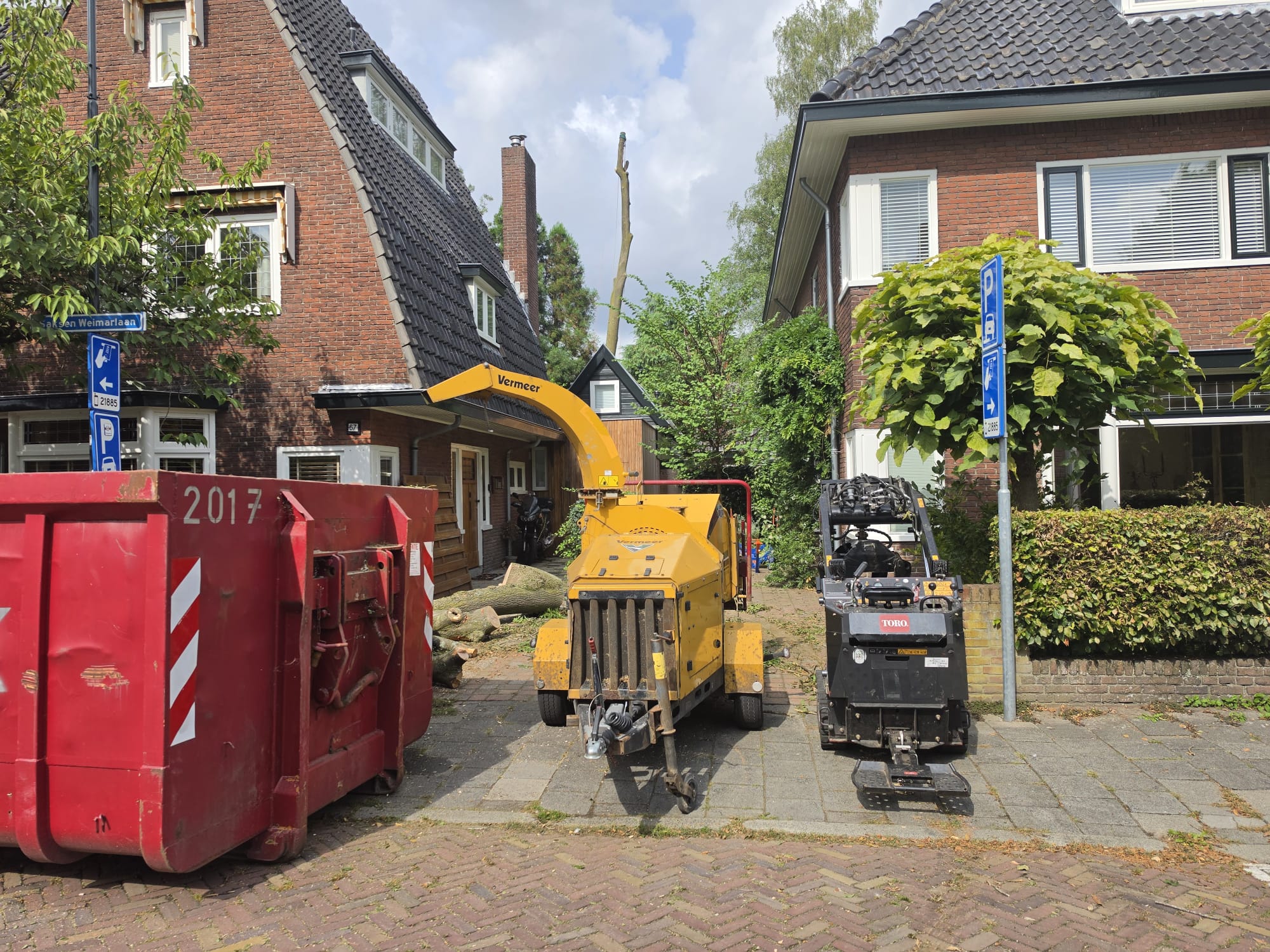 Versnipperaar en minikraan opgesteld langs de straat bij de rooiklus
